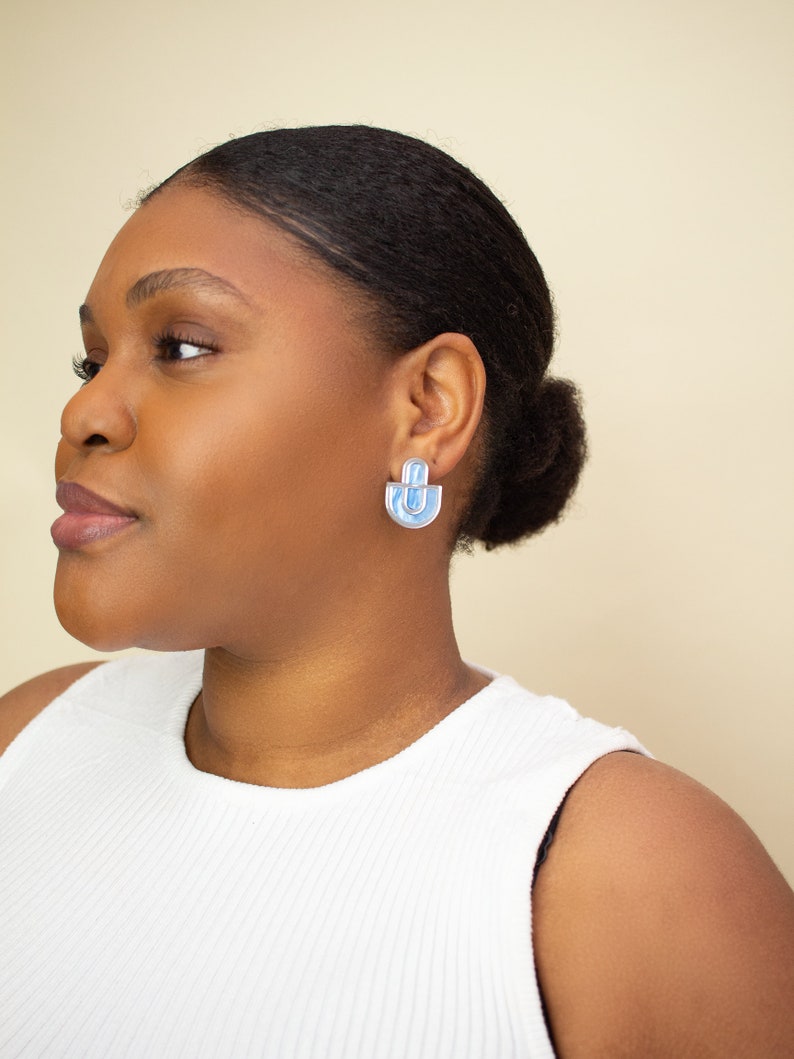 A model wearing blue statement stud earrings.
