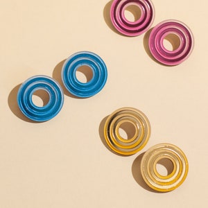 A group photo of wearing  circular multicolored statement stud earrings.