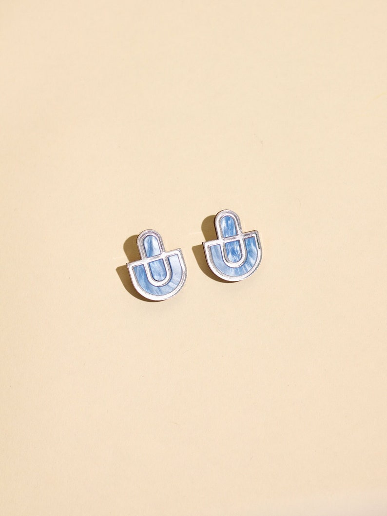 A pair of blue and silver statement stud earrings.