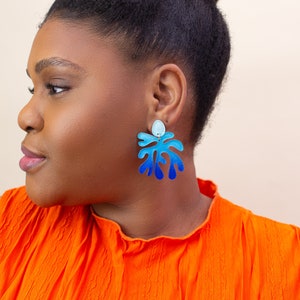 A model wearing a pair of ombre blue Matisse statement dangle earrings.