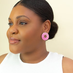 A model wearing  pink circular multicolored statement stud earrings.
