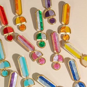 A group of acrylic dangle statement hoop earrings in different colors: red, orange green, yellow, blue purple, pink, and turquoise.