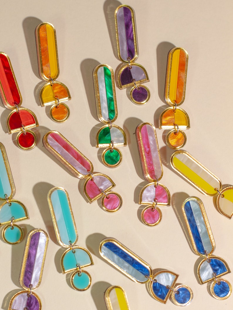 A group of acrylic dangle statement hoop earrings in different colors: red, orange green, yellow, blue purple, pink, and turquoise.