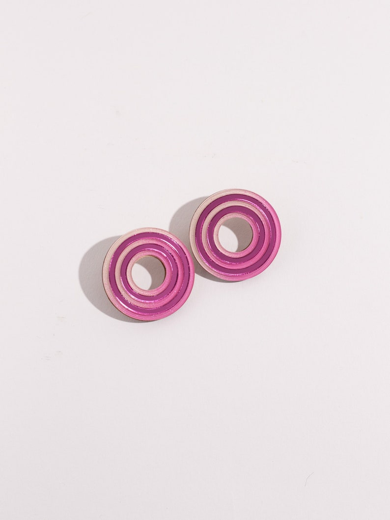 A pair of pink circular multicolored statement stud earrings.