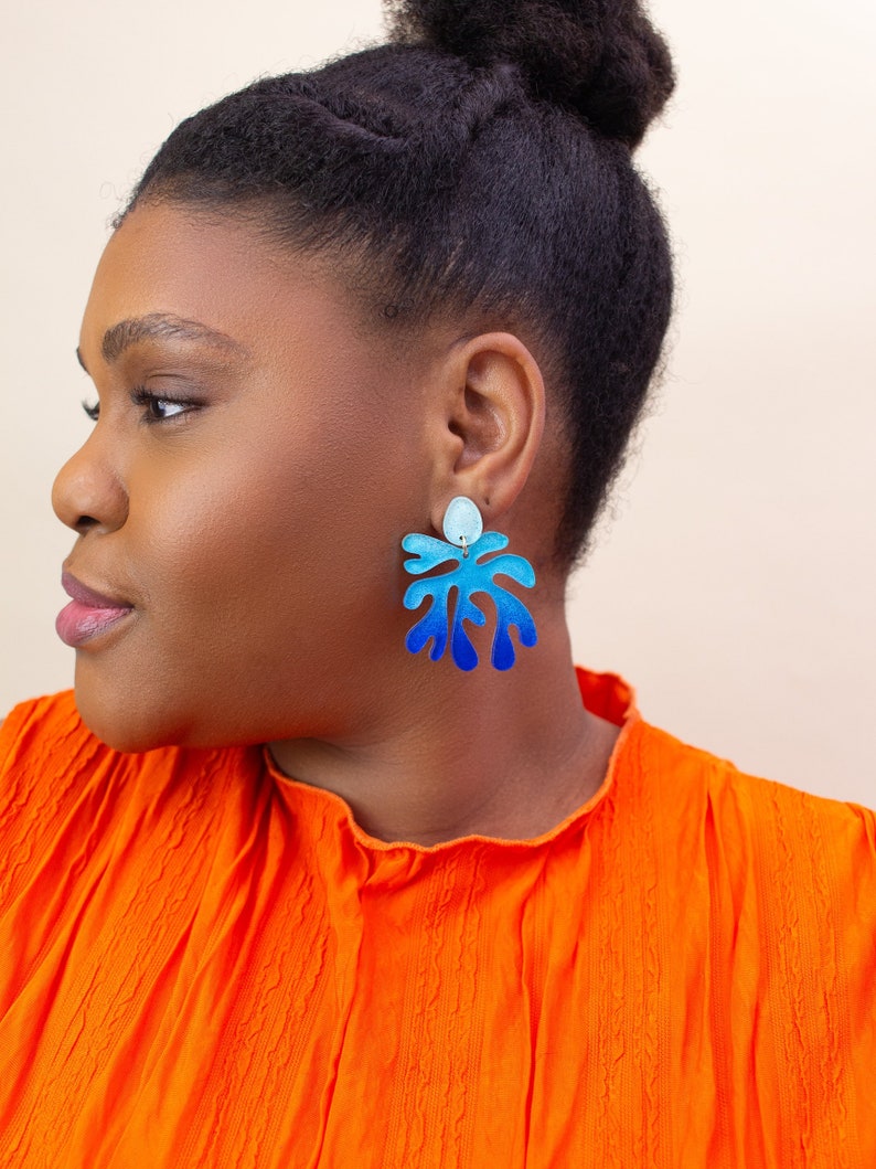 A model wearing a pair of ombre blue Matisse statement dangle earrings.