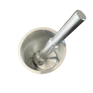 Könnte beinhalten: Ein silbernes Mörser- und Stößel-Set. Der Mörser ist ein schalenförmiger Behälter mit einer glatten, glänzenden Oberfläche. Der Stößel ist ein zylindrisches Werkzeug mit abgerundetem Ende. Das Set ist aus Metall und zum Mahlen und Zerkleinern von Zutaten gedacht.