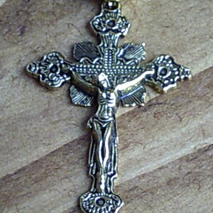 K&ouml;nnte beinhalten: Ein goldfarbenes Metallkreuz mit einem detaillierten Design. Das Kreuz zeigt eine Figur von Jesus Christus am Kreuz.
