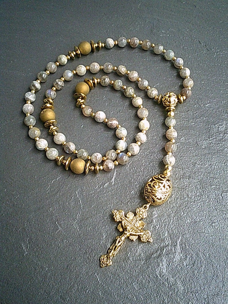 May include: A gold and grey gemstone rosary with a gold cross and a gold bead at the end.
