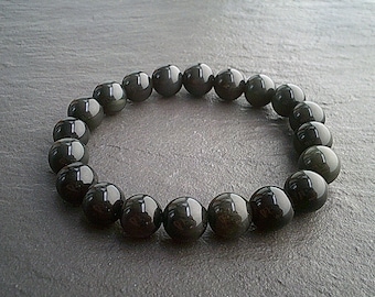 May include: A black obsidian beaded bracelet with a shiny finish. The bracelet is made of round beads and is approximately 7.5 inches in length.