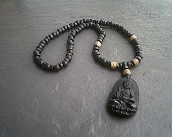 Puede incluir: Collar de cuentas negras con un colgante de Buda tallado en negro y detalles dorados.