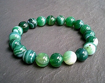 Puede incluir: Un brazalete de cuentas de ágata verde con rayas blancas. Las cuentas son redondas y lisas.