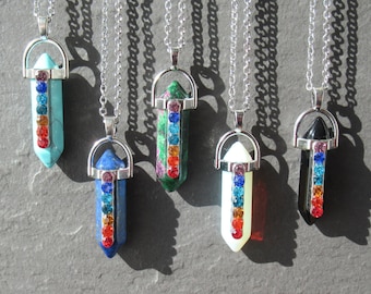 Puede incluir: Siete collares de plata con colgantes de punta de cristal. Cada colgante presenta un cristal de color diferente con un arcoíris de pedrería en el centro.