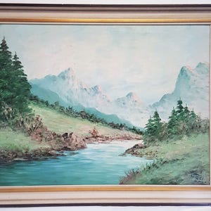 May include: A framed oil painting depicting a serene landscape with a winding river flowing through a valley surrounded by snow-capped mountains and lush green trees. The painting is signed "Witzel" in the lower right corner.