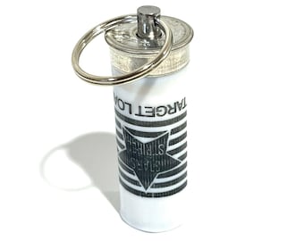 May include: A silver keychain with a white cylinder attached. The cylinder has a black and white design with the text "TARGET LOCK" and a five-pointed star.