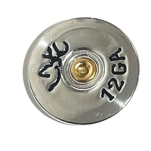 May include: A silver shotgun shell with a black deer head design and the text "12 GA" printed on the side.