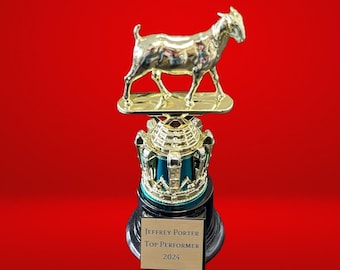 May include: A gold-colored trophy with a goat figurine on top. The base of the trophy is black with a green and gold crown design. A plaque on the base reads "Jeffrey Porter Top Performer 2024".