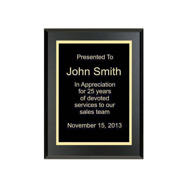 May include: Black plaque with gold trim and text that reads "Presented To John Smith In Appreciation for 25 years of devoted services to our sales team November 15, 2013"