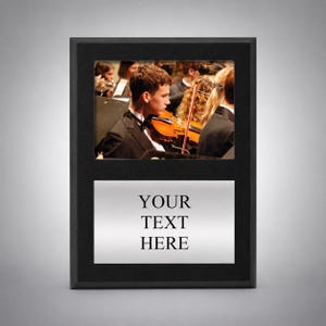 May include: A rectangular black plaque featuring a top horizontal window displaying a photograph of a musician playing a violin in an orchestra, and a bottom silver-toned metal plate with the black printed text YOUR TEXT HERE.