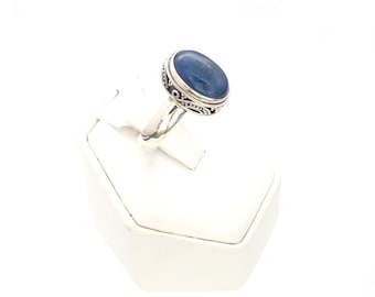 May include: A silver ring with a blue oval gemstone set in a decorative filigree design.