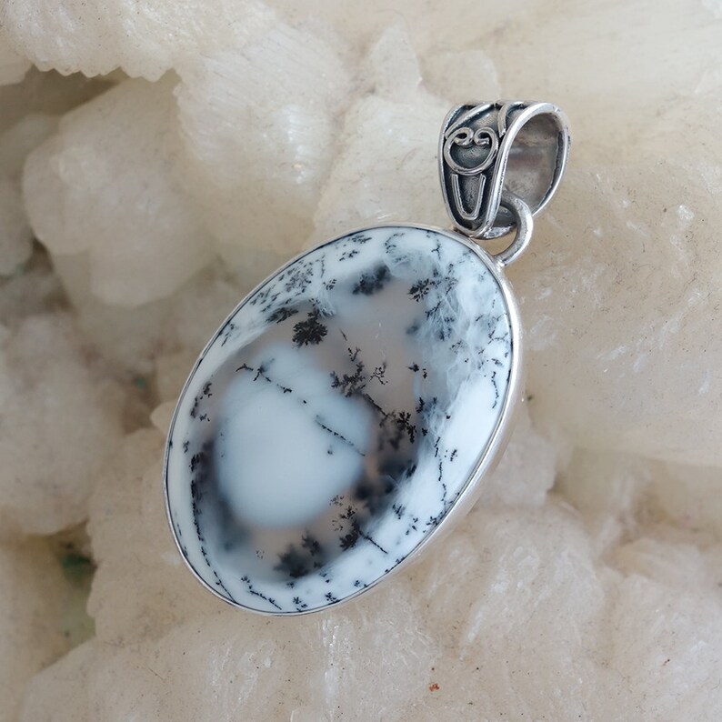 May include: A silver pendant featuring a white and gray dendritic agate stone with a detailed silver bail.