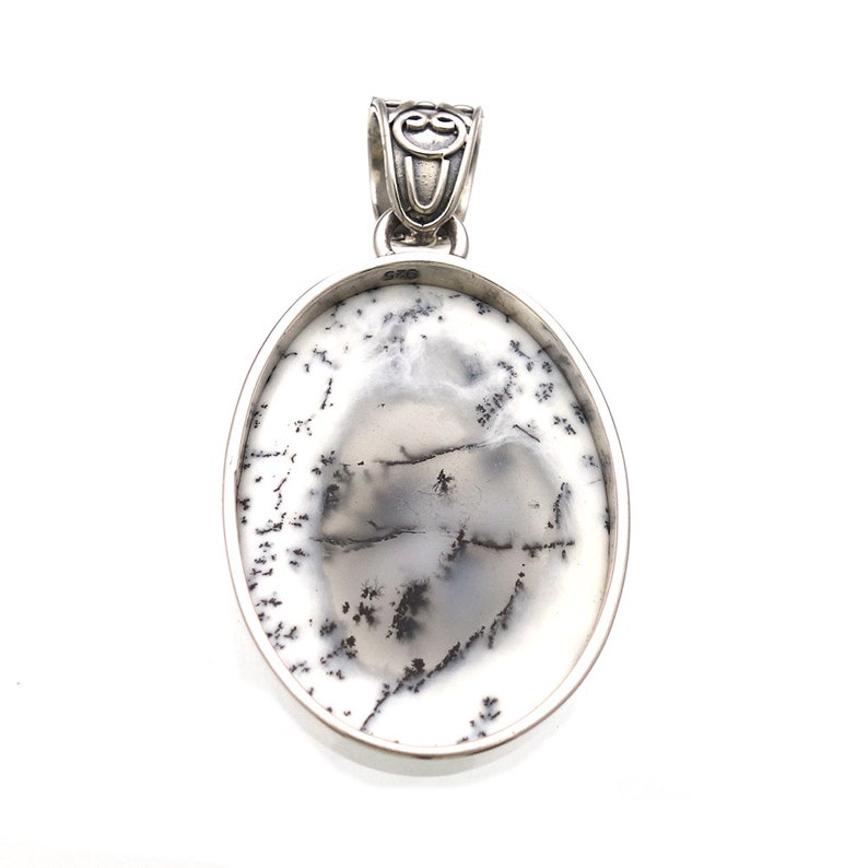 May include: A silver pendant with an oval-shaped dendritic agate stone. The stone is white with black dendritic patterns.