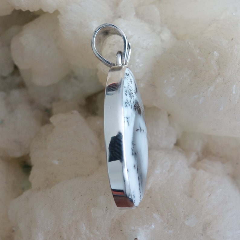 May include: A silver pendant with a white and black agate stone. The stone is oval shaped and has a smooth, polished finish.