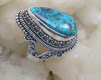 May include: A silver ring with a large, teardrop-shaped turquoise gemstone. The ring has intricate, detailed silverwork.