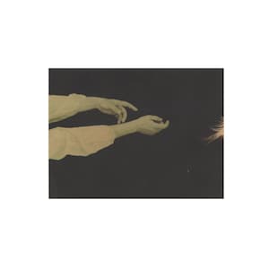 Op de afbeelding: Een vintage foto met twee armen en handen tegen een donkere achtergrond. De armen zijn gekleed in lichtgekleurde mouwen, met één hand die uitreikt naar een gloeiend, veervormig object. De afbeelding heeft een zachte, dromerige kwaliteit.