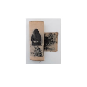 May include: A rectangular piece of light brown fabric featuring a black and white photographic print of a person sitting with a plant motif below, alongside a smaller square piece of fabric with a dark, abstract, ink-like black and white pattern.
