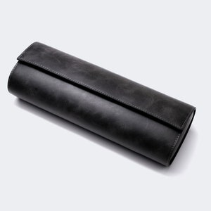 May include: A black leather watch roll for storing and protecting watches.