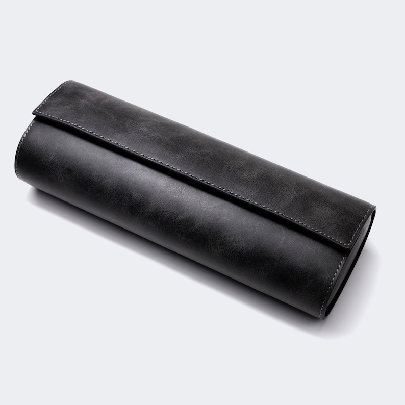 May include: A black leather watch roll for storing and protecting watches.