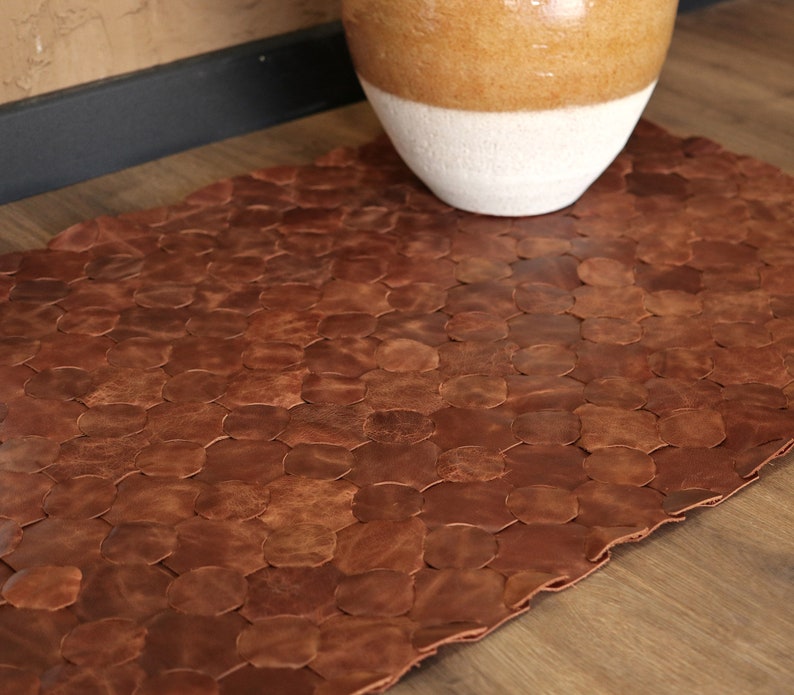 May include: A brown leather rug made of individual pieces of leather sewn together in a honeycomb pattern.