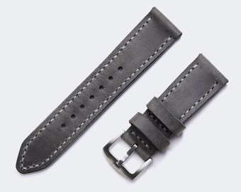 May include: A grey leather watch strap with white stitching and a silver buckle.