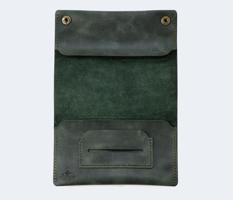 Puede incluir: Una cartera de cuero verde oscuro con dos cierres a presi&oacute;n y un bolsillo &uacute;nico en la parte delantera. La cartera est&aacute; abierta para revelar un solo bolsillo en el interior.