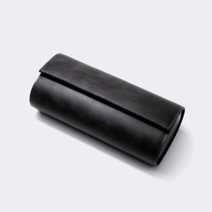 May include: A black leather watch roll with a zipper closure. The roll is designed to hold multiple watches.