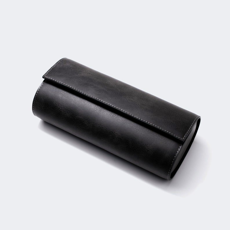 May include: A black leather watch roll with a zipper closure. The roll is designed to hold multiple watches.