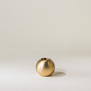 May include: A gold-colored metal candle holder shaped like a sphere.