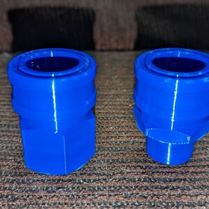 May include: Two bright blue, 3D-printed plastic connectors. One is a hexagonal shape, the other has a rounded base. Both have a circular opening at the top. The connectors are likely for plumbing or other mechanical applications.
