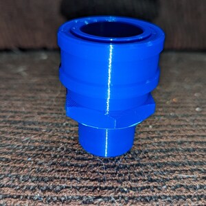 May include: A vibrant blue, 3D-printed plastic component. The object has a cylindrical shape with a hexagonal base and a circular opening at the top. The component is approximately 2 inches tall.