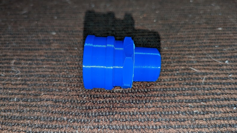 May include: A bright blue plastic fitting with a cylindrical shape. The fitting has a series of ridges and a hexagonal section in the middle. The object is likely a plumbing or mechanical component.