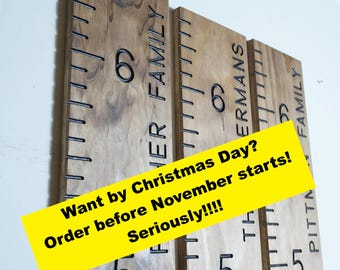May include: Three vertical wooden growth charts with black measurement markings and numbers 5 and 6. The boards feature engraved text including "FISHER FAMILY", "THE ERMANS", and "PITTMAN FAMILY". A yellow banner displays "Want by Christmas Day? Order before November starts! Seriously!!!!"