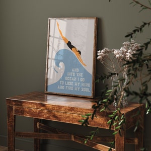 May include: A framed print with a blue and white illustration of a person diving into a wave. The text below the image reads "And into the ocean I go to lose my mind and find my soul."