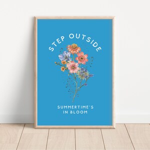 May include: A blue poster with the text "STEP OUTSIDE SUMMER TIME'S IN BLOOM" in white. A bouquet of pink, blue, and yellow flowers is in the center of the poster.