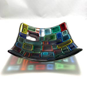 Puede incluir: Un plato de vidrio negro con un dise&ntilde;o de mosaico de cuadrados coloridos. Los cuadrados son de varios tonos de rojo, verde, azul, amarillo y naranja.