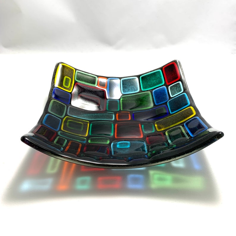 Puede incluir: Un plato de vidrio negro con un dise&ntilde;o de mosaico de cuadrados coloridos. Los cuadrados son de varios tonos de rojo, verde, azul, amarillo y naranja.