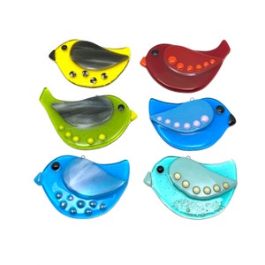 May include: Six glass bird ornaments in various colors, including yellow, red, green, blue, and teal. Each bird has a unique design and features small, raised dots.