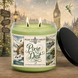 May include: A two-wick candle in a clear glass jar with light green wax. The label features the text Main Street Melts Candle Co. Pixie Dust and www.MainStreetMeltsCandleCo.com, alongside illustrations of a ship wheel, a skull, and a treehouse.