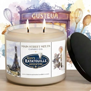 Pode incluir: Uma vela de dois pavios num frasco de vidro transparente com tampa preta. O rótulo apresenta o texto Main Street Melts Candle Co. e Remy's Ratatouille Adventure, uma ilustração da Torre Eiffel, um rato com uma colher e um chapéu de chef.