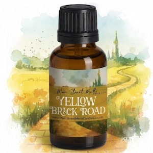 May include: A small amber glass bottle with a black ribbed screw cap. The label features a watercolour illustration of a yellow brick road leading to a distant castle, with the text Main Street Melts Candle Co. and YELLOW BRICK ROAD.