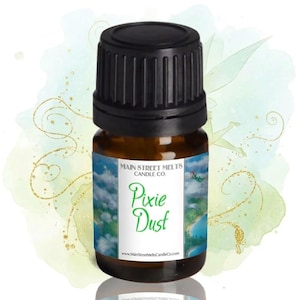 May include: A small amber glass bottle with a black cap. The label reads "Main Street Melts Candle Co." and "Pixie Dust" in green script. The label features a whimsical landscape with a fairy. The background has a watercolor effect.